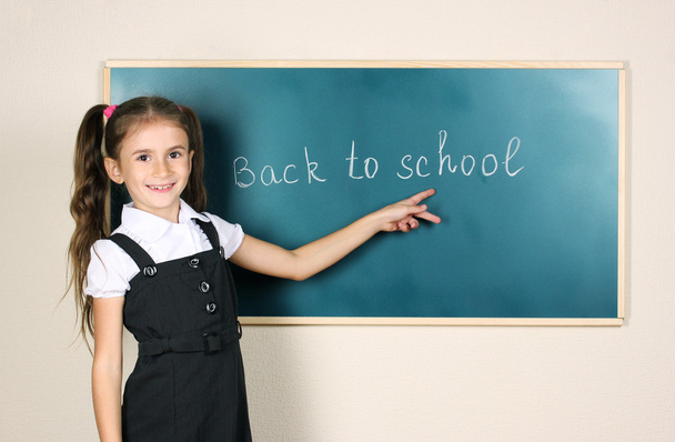 Beautiful little girl standing near blackboard in the classroom - Foto, Imagem