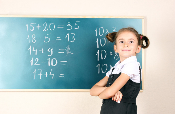 Beautiful little girl standing near blackboard in the classroom - Valokuva, kuva