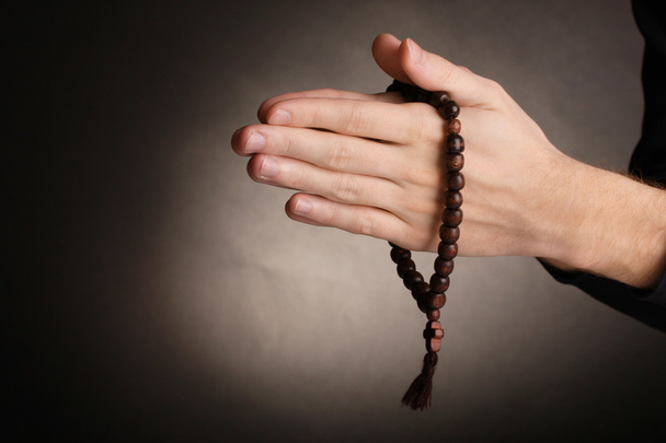 Hands holding wooden rosary on grey background - Foto, afbeelding