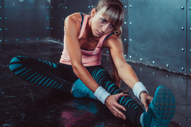 Fit woman doing stretching exercises her muscles back and legs before a training warm up at gym concept fitness, sport, lifestyle. - Photo, Image