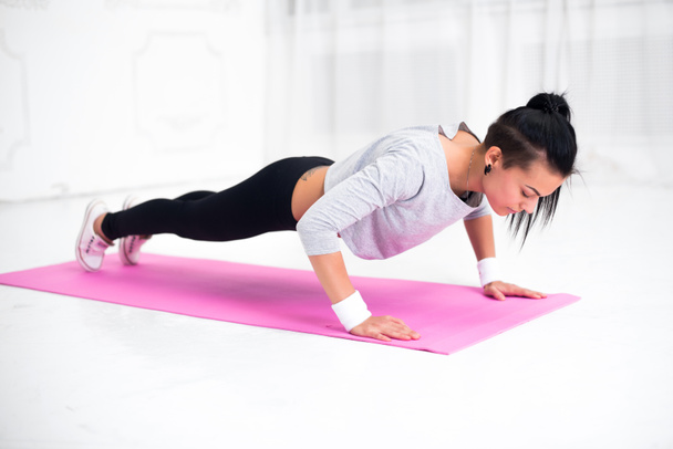Young latin woman warming up and doing push ups at home fitness healthy lifestyle diet concept. - Foto, afbeelding