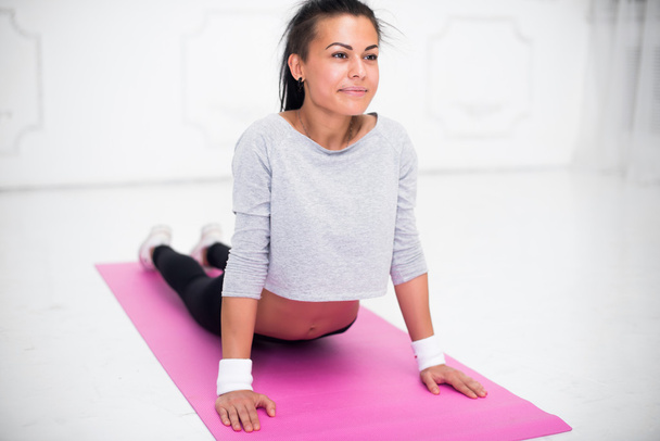 Девушка делает разогрев упражнения для позвоночника, backbend, дуга растяжения спины тренировки на дому или йоги класса
 - Фото, изображение