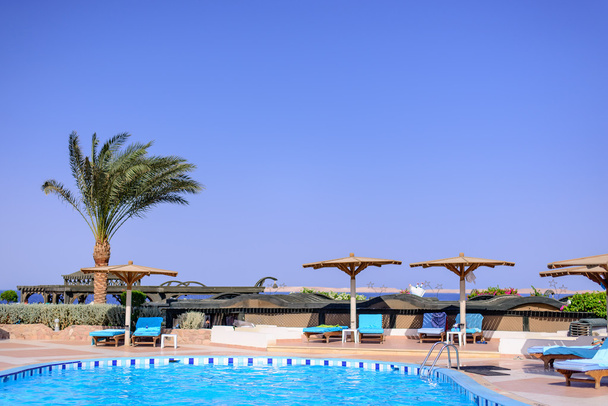Swimming pool and umbrellas at a resort - Zdjęcie, obraz