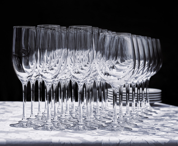Wine glasses with plates on the table. Black background - Photo, Image
