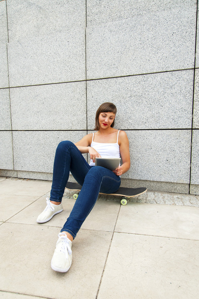 Nuori tyttö istuu rullalauta kaupungin tabletti w
 - Valokuva, kuva