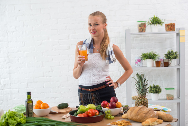 Woman preparing dinner in a kitchen, drinking juice concept cooking, culinary, healthy lifestyle. - Foto, Bild
