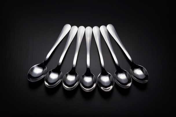 Seven spoons on black background - Foto, imagen