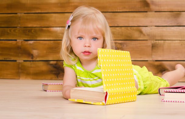 niña rubia con libros en el interior
 - Foto, Imagen