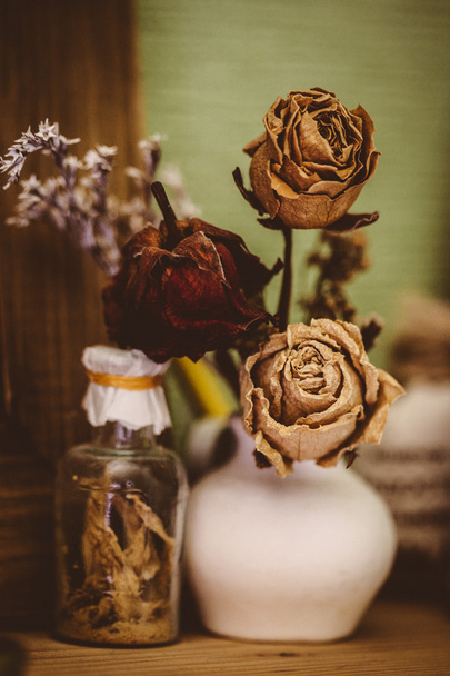 Vintage style still life  with three dried roses and bottle - Photo, Image