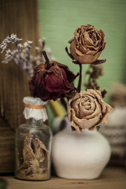 Винтажный стиль натюрморт с тремя сушеными розами и бутылкой
 - Фото, изображение