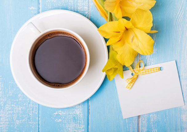 Cup of coffee, yellow flowers and blank paper card on blue woode - Valokuva, kuva
