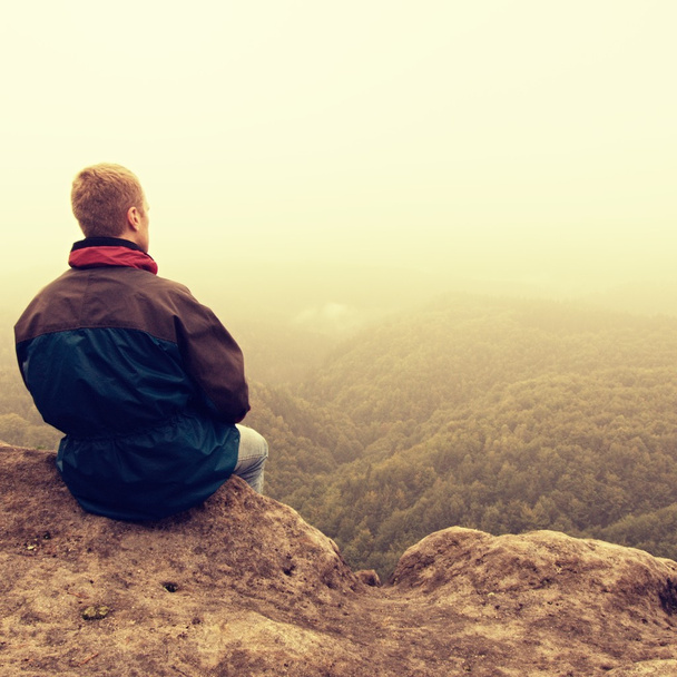 Un día triste y melancólico. El hombre en la venganza de la roca por encima de vally profundo. Turista en la cima de la roca arenisca mirando a la niebla
. - Foto, imagen