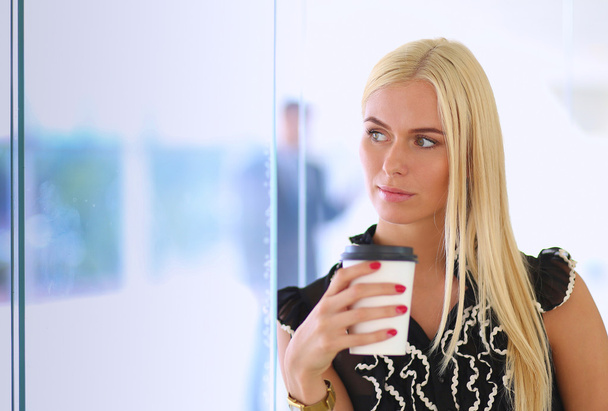 Femme d'affaires tenant une tasse de café debout dans le bureau
 - Photo, image
