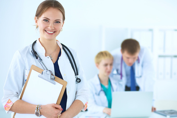 Attractive female doctor  with folder in front of medical group - Photo, image