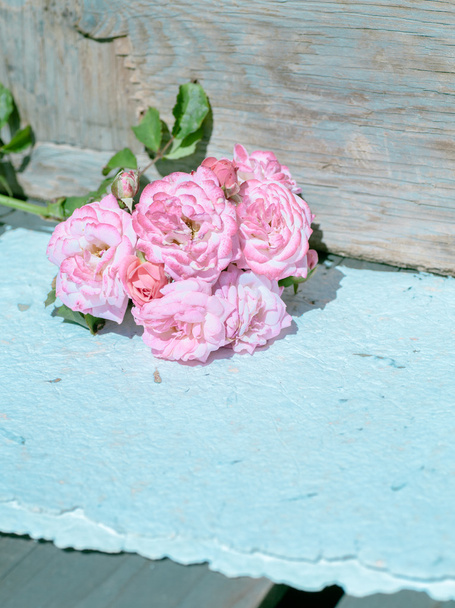 Рожеві троянди з паперами на дерев'яному столі
 - Фото, зображення