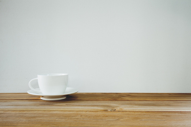 coffee cup on wooden table over white background. Vintage tone - Foto, imagen