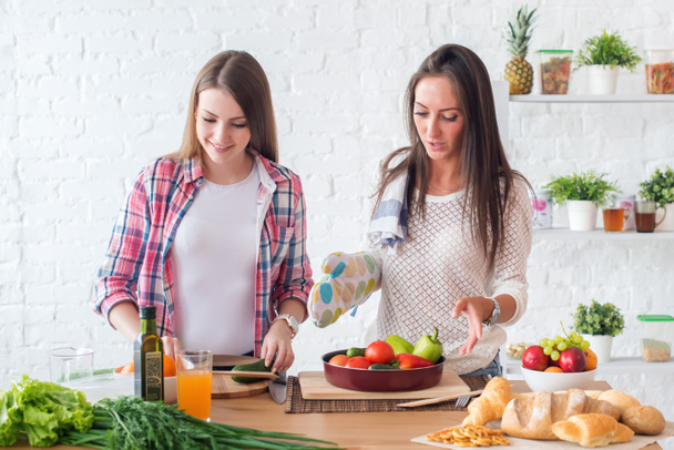 Dos chicas preparando la cena en un concepto de cocina cocina, culinaria, estilo de vida saludable
. - Foto, Imagen