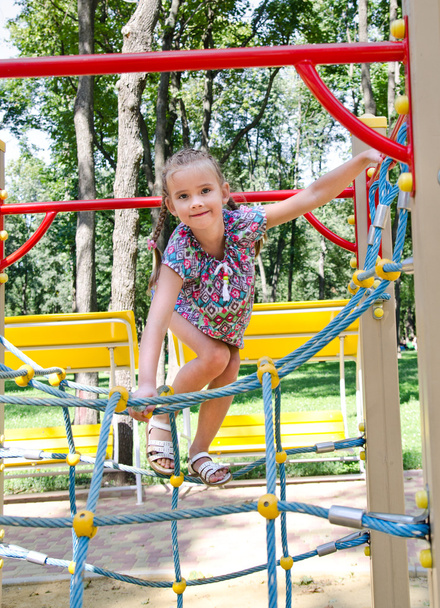 Sorrindo menina brincando em equipamentos de playground
  - Foto, Imagem