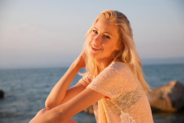 Beautiful young blonde woman resting on a beach at dusk in early - Foto, Bild