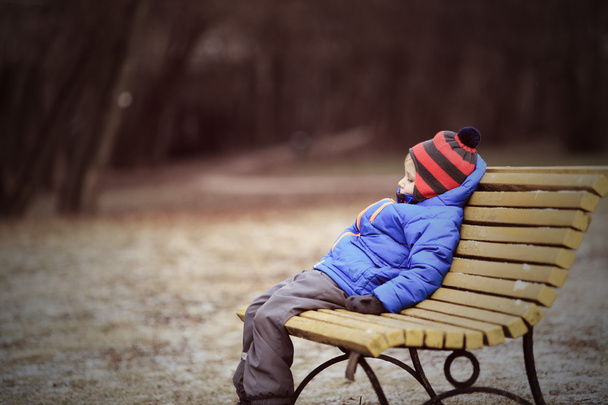 eenzame kind zittend op de Bank in winter park - Foto, afbeelding