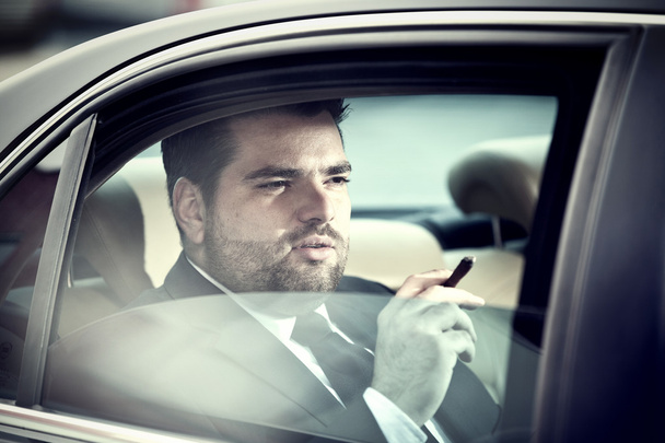 Homem no banco de trás de um carro fumando
 - Foto, Imagem