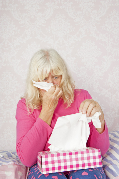 Woman on bed blowing nose - Photo, Image