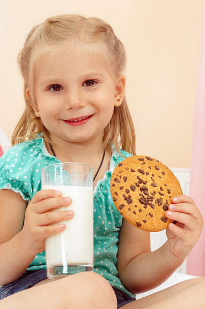 Cheerful little girl with chocolate chip cookies and milk - Foto, afbeelding