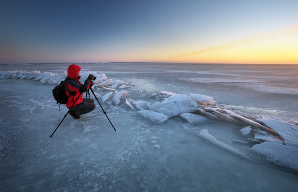 Valokuvaaja ottaa kuvia joen rannalla talvella
 - Valokuva, kuva