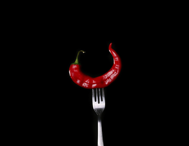 Paperi chili haarukalla mustalla pohjalla
 - Valokuva, kuva