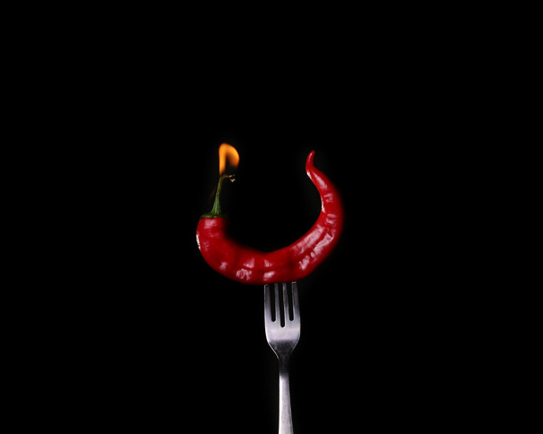 Fork impale to red hot chili on black background. - Photo, Image