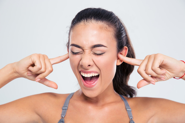 Vrouw die betrekking hebben op haar oren met vingers en schreeuwen - Foto, afbeelding
