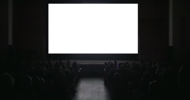 Visores en sala de cine oscuro con pantalla en blanco - Imágenes, Vídeo