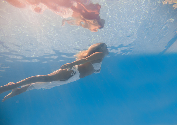Young woman swimming underwater - Fotó, kép