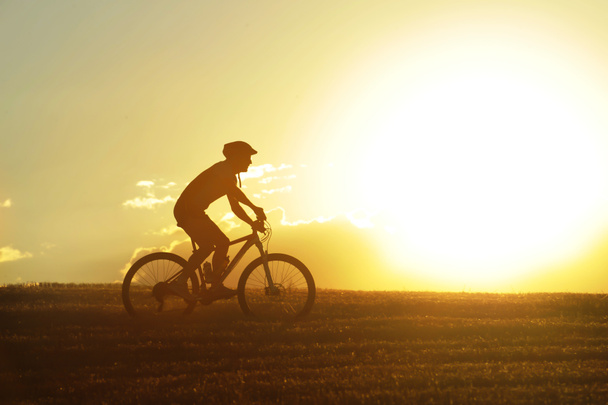 profile silhouette sport man riding cross country mountain bike - Foto, afbeelding