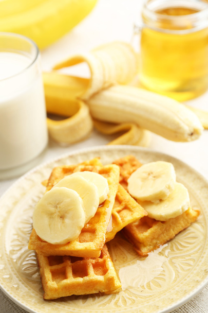 Sweet homemade waffles with sliced banana on plate, on light background - Foto, immagini
