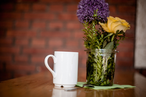Cup of coffee and beautiful flowers on wooden background - Photo, Image