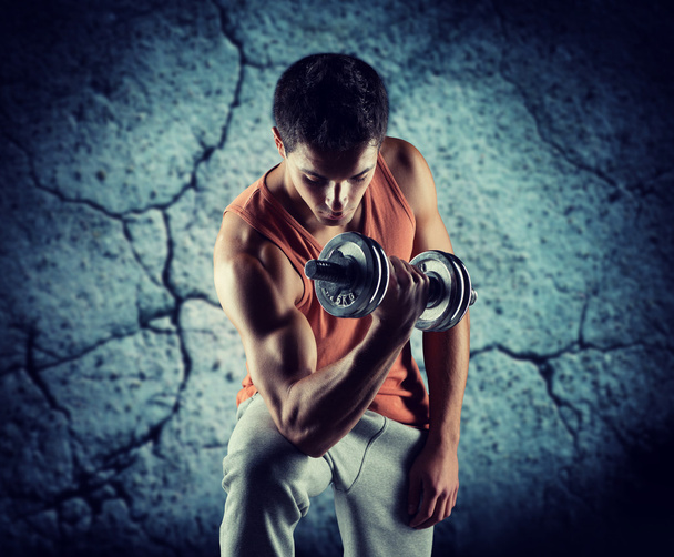 young man with dumbbell flexing biceps - Zdjęcie, obraz