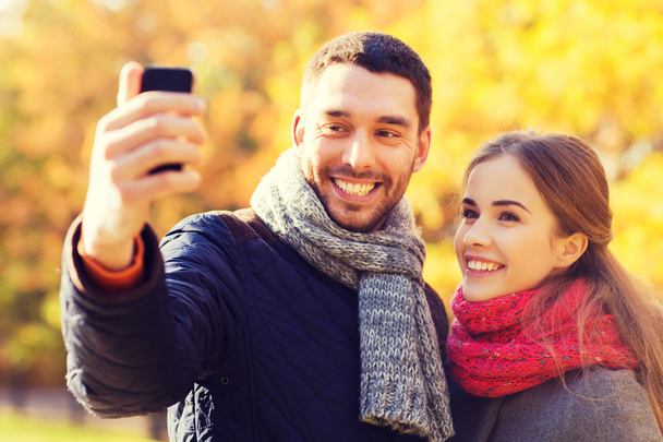 smiling couple with smartphone in autumn park - Foto, immagini