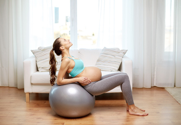 happy pregnant woman exercising on fitball at home - Foto, immagini