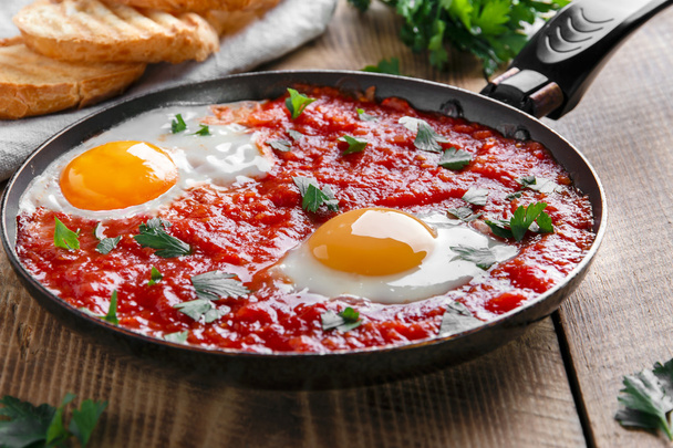смажені яйця в томатному соусі на сковороді
 - Фото, зображення