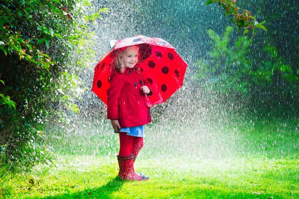 秋の雨で遊んで赤いジャケットの少女 - 写真・画像