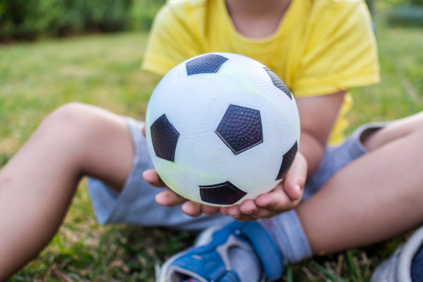 little boy is holding a ball with his both hands - Foto, imagen