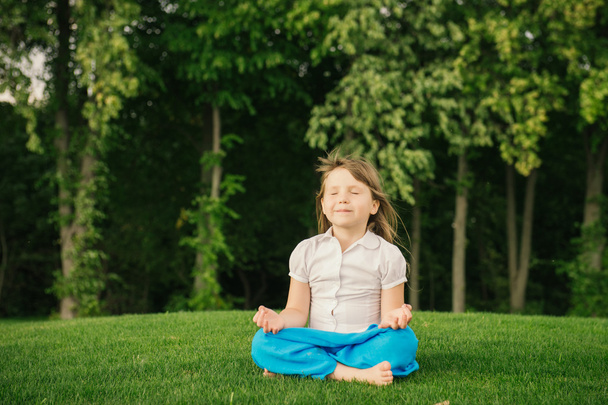 Smiling little girl in lotus position - Foto, afbeelding
