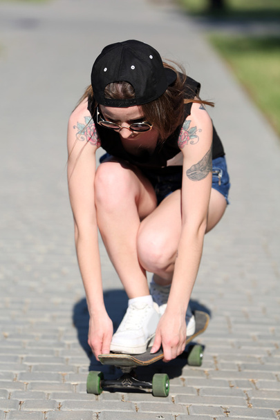 Beautiful tattooed girl with skateboard, outdoors - Foto, afbeelding