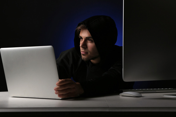 Hacker with computer and laptop on dark background  - Фото, изображение