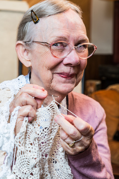 Elderly woman in pink sweater crocheting - Foto, immagini