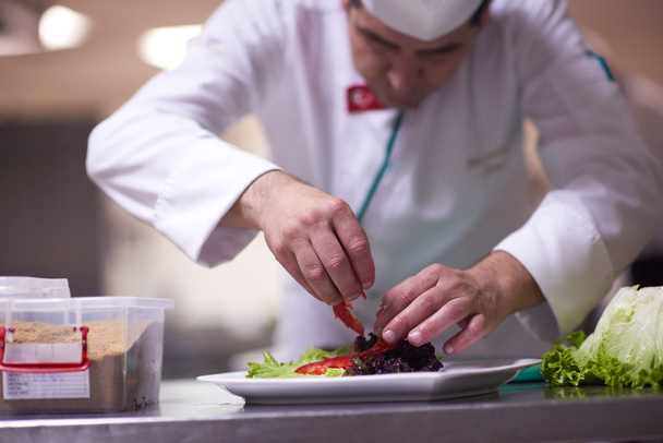 chef in kitchen preparing and decorating food - Foto, imagen