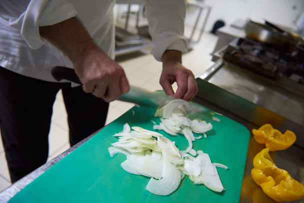 chef in kitchen slicing vegetables with knife - Foto, afbeelding