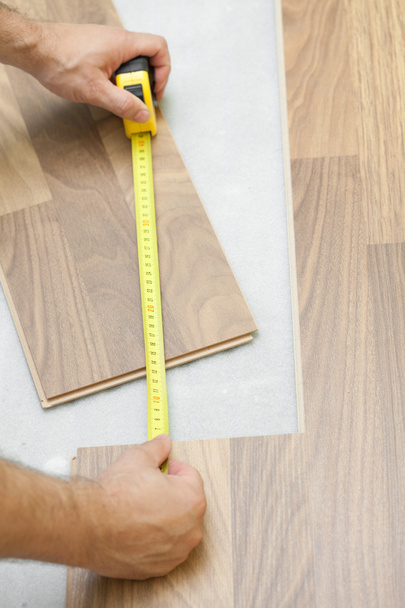 Carpenter measuring wooden floor plank - Fotó, kép