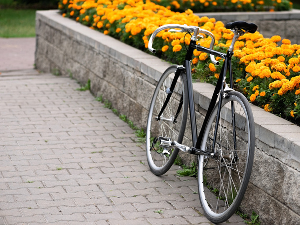 Vintage bike over flowerbed with yellow flowers - Foto, Imagem